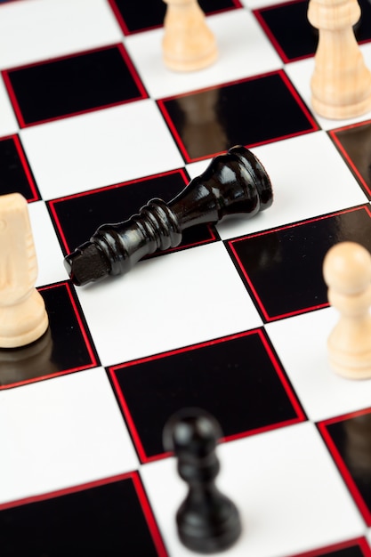 Black queen lying at the chessboard while white standing 