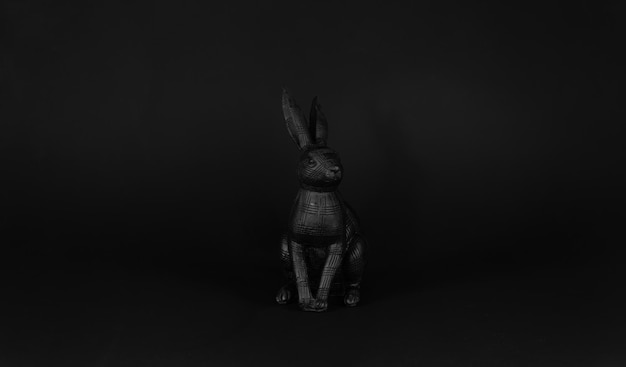 A black rabbit statue sits in a dark room.