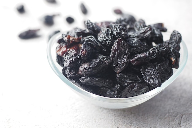 Black raisin in a bowl on white background