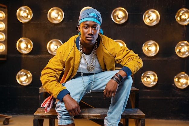 Black rapper in cap sitting on the steps