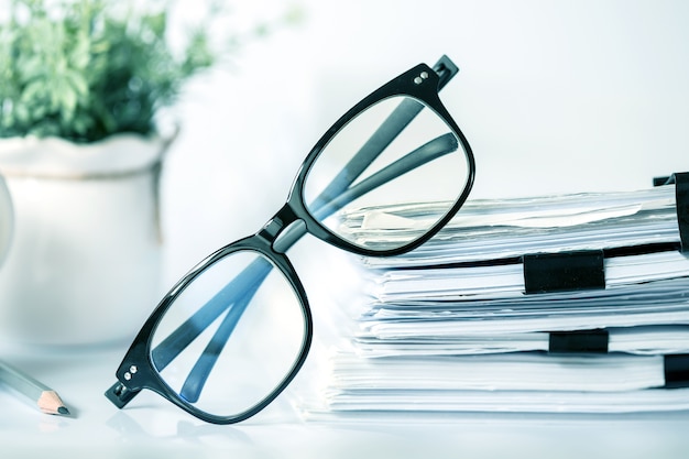 black reading eyeglasses on the stacking of office paper