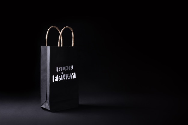 Black recyclable paper shopping bag with lettering on black background, black friday sale concept, banner.