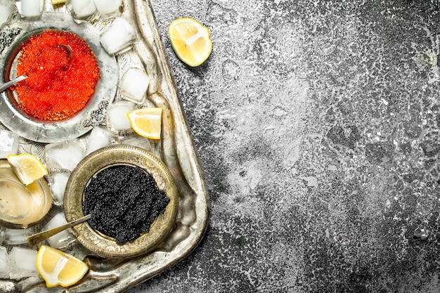 Black and red caviar in bowls on old tray.