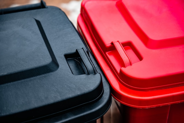 Black and red garbage containers for separation and sorting  Glass, plastic, paper and household waste. Waste sorting, the concept of eco-friendly garbage collection.