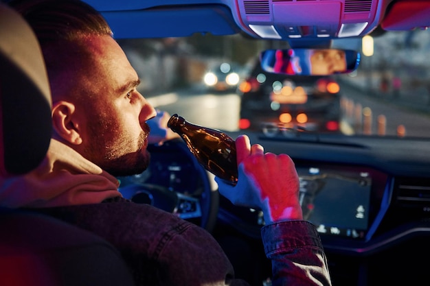 黒と赤の警察のライト飲んだり運転したりしないでください彼の自動車の中でファッショナブルな服を着たハンサムな剃っていない男の背面図