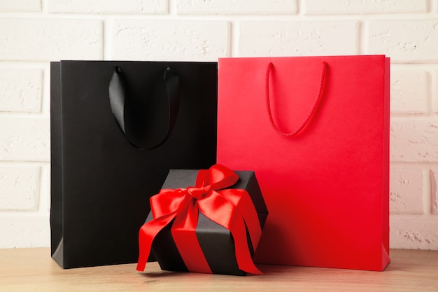 Black and red shopping bags with gift on light background. Black friday. Top view