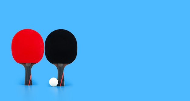 青いテーブルの上のボールと黒と赤のテニスラケット