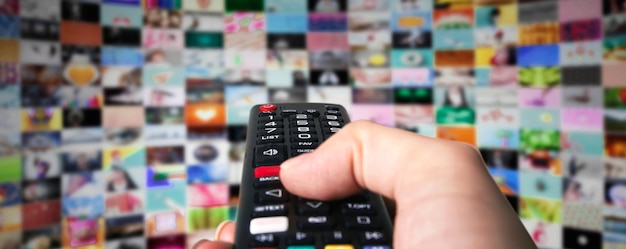 Photo black remote control in hand over smart tv background, channel switching