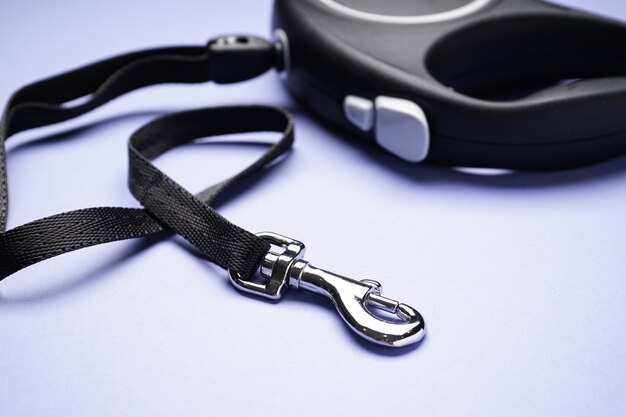 Black retractable dog leash on a purple background. Close-up.