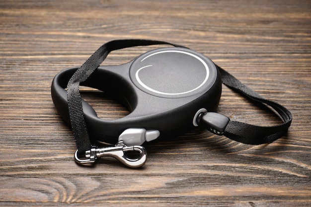 Black retractable leash for dogs on a wood background. Close-up.