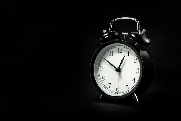 black retro alarm clock in dark background.For night time concept.