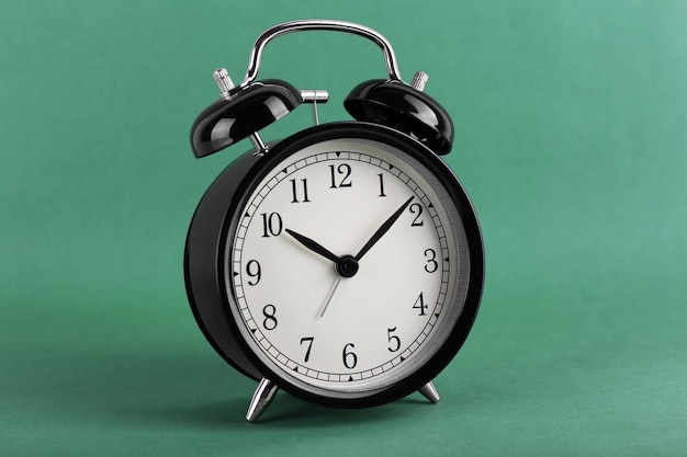 Black retro alarm clock on green background