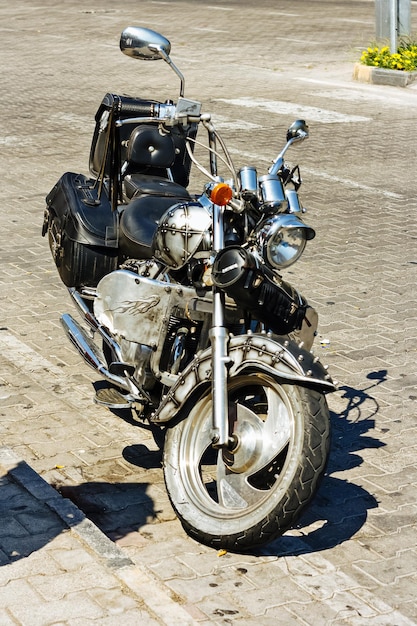 Black retro motorcycle chopper stands on site without driver View from the side