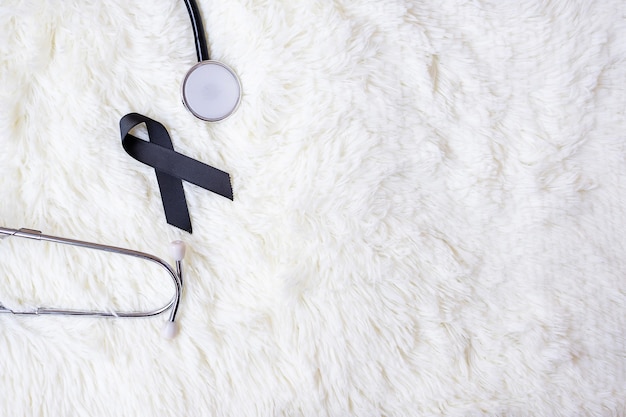 black ribbon and stethoscope on white furry background