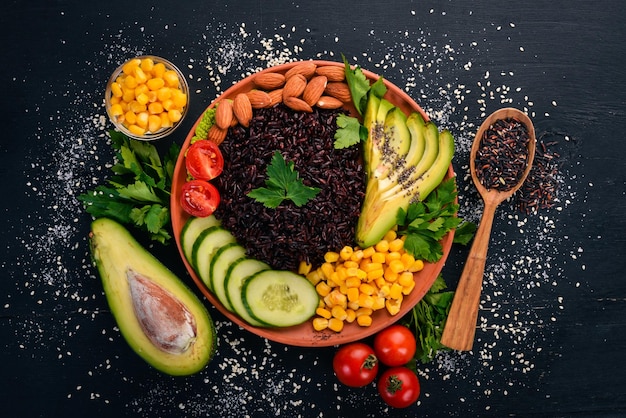 Black rice avocado cucumber corn and almonds On a wooden background Top view Free space for your text