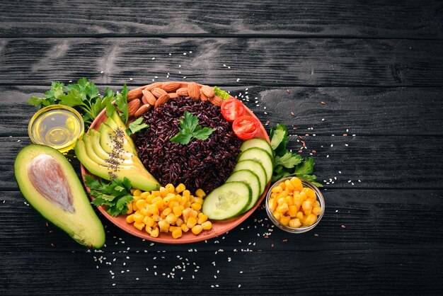 Black rice avocado cucumber corn and almonds On a wooden background Top view Free space for your text