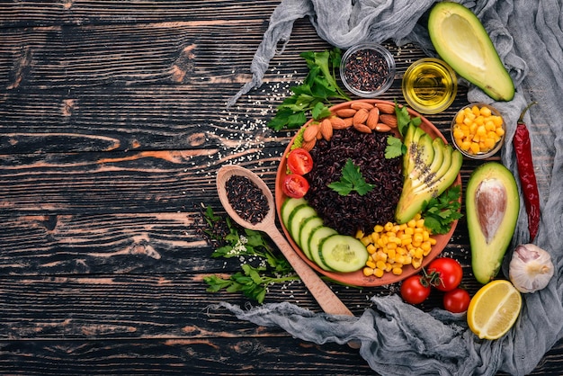 Black rice avocado cucumber corn and almonds On a wooden background Top view Free space for your text