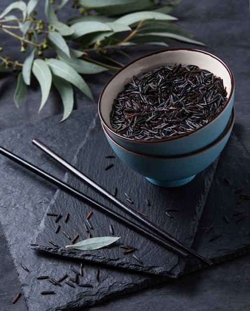 Black rice in a blue bowl on a board