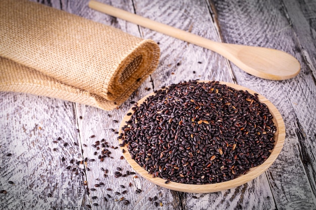 The black rice on old wooden table. Selective focus