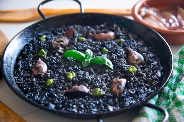 해산물과 생선을 곁들인 흑미 빠에야. 전통적인 스페인 요리법.