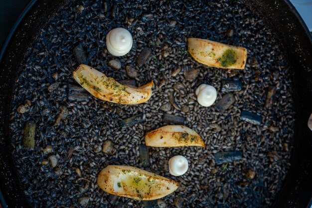 Black rice with cuttlefish and young garlic a dry rice dish cooked in paella or in a clay pot a characteristic flavor of Valencian Mediterranean cuisine Spain