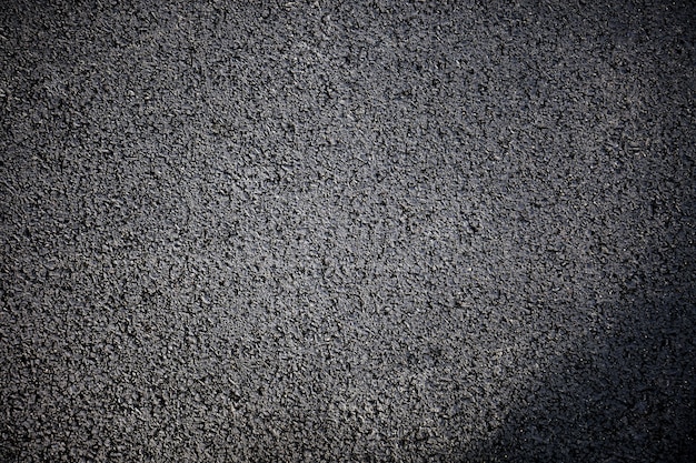 Black rough asphalt road texture background, top view. close up.