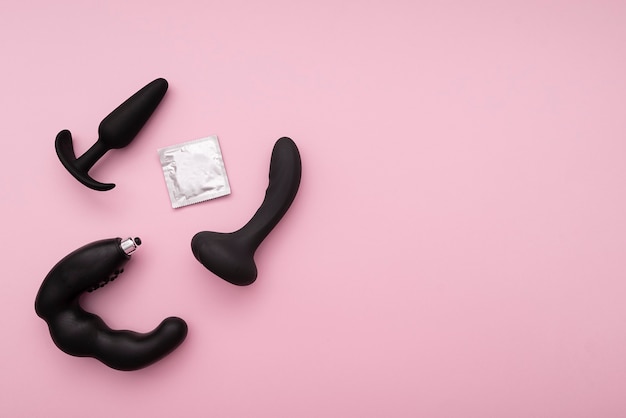 black rubber sex toys, silicone sex toy and condom on pink background, sex composition, layout