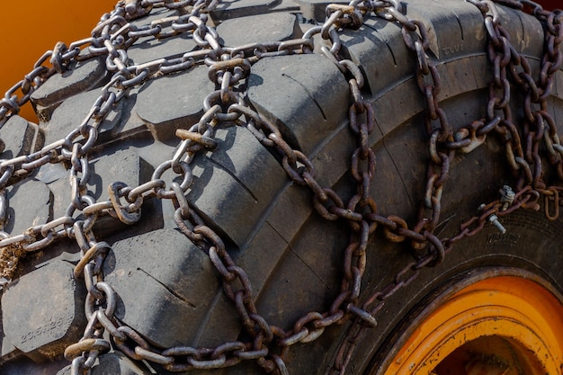 Black rubber wheel of heavy machinery with iron chain