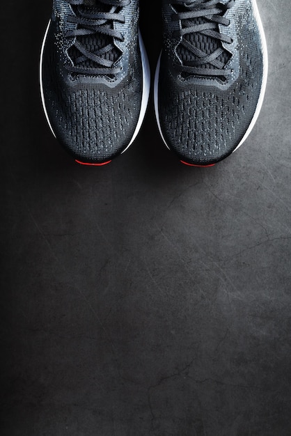 Black running shoes with mesh and black laces close-up on a dark background. Top view of sports sneakers.