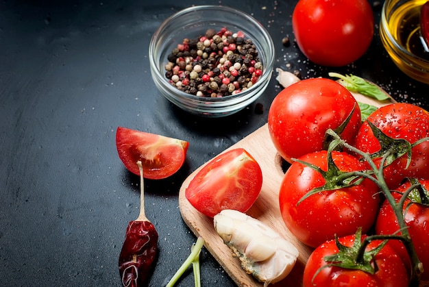 Photo black rustic tabletop with branch of tomatoes and herbs, top view