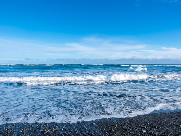 Black sand diamond beach with wave and snow mountains in Iceland