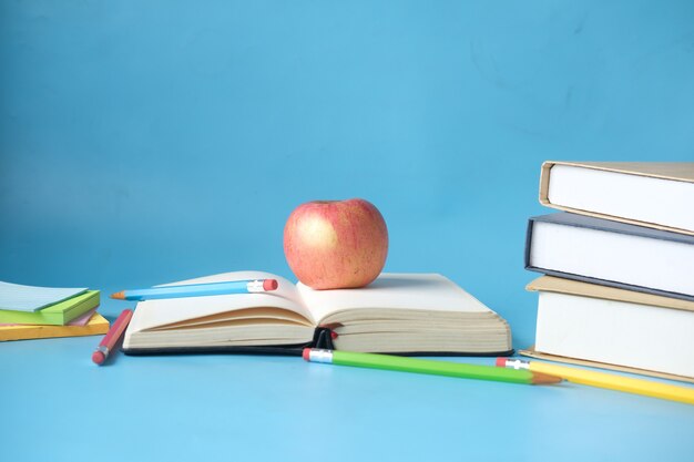 Black to school concept with apple on a book on blue