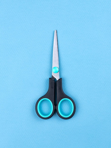 Photo black scissors isolated on blue background