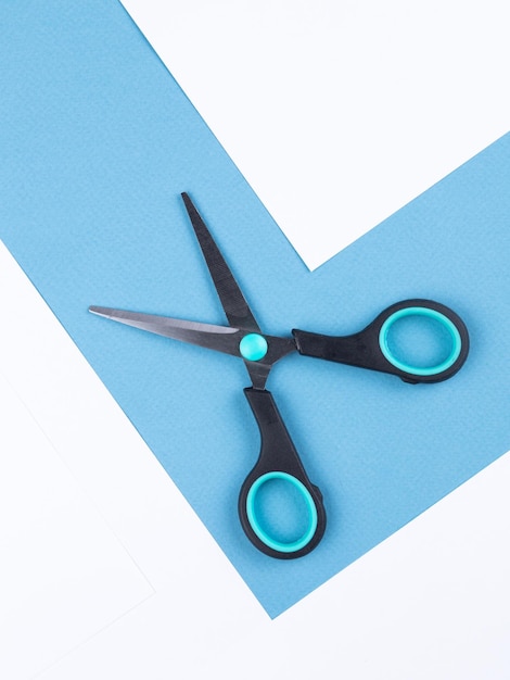 Black scissors isolated on white and blue background