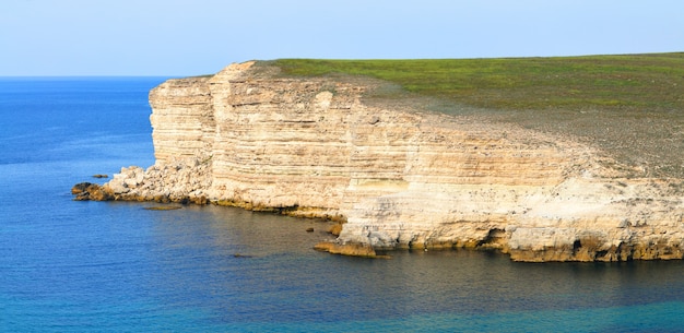 Black sea rocks at coastline with clear blue waters and blue sky