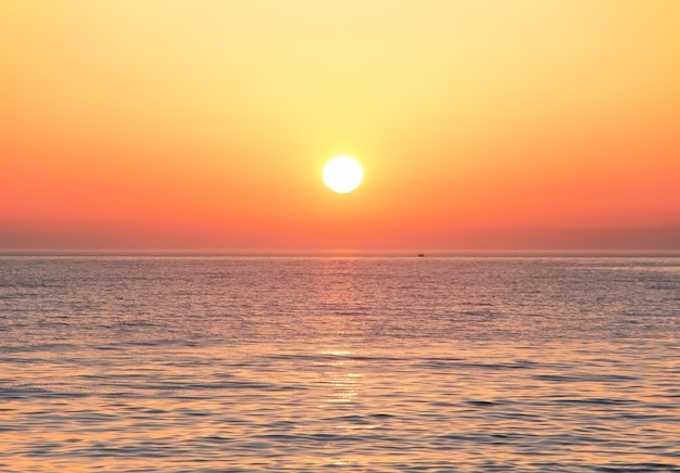 Черное море на закате. Большое желтое солнце под поверхностью моря. Сочи, Россия.