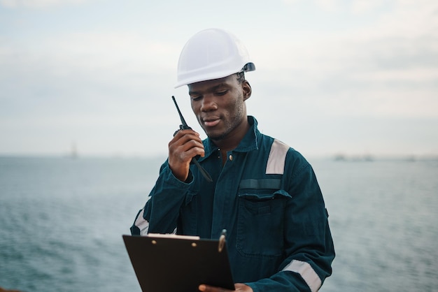 Photo black seaman reading document to colleague via radio