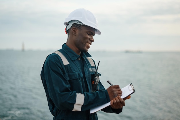 Photo black seaman writing down data on clipboard