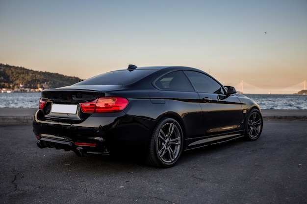 Black sedan parked on the road with red xenon lights