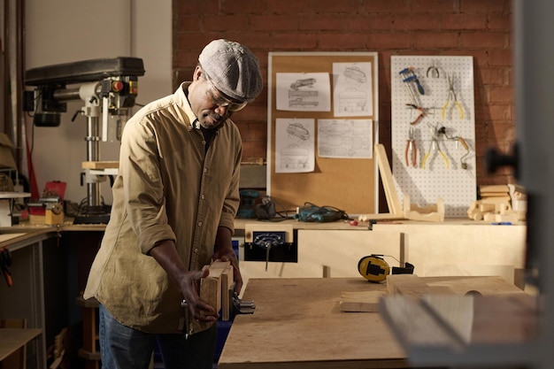 Photo black senior man as carpenter using equipment in woodworking shop