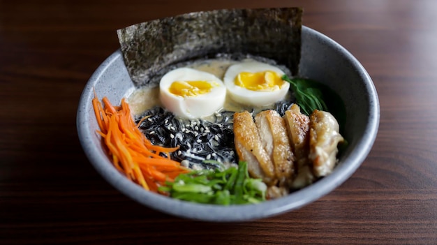 Black Sesame Ramen — это кремовый и успокаивающий рамен с бульоном из черного кунжута в сочетании с курицей-гриль, яйцом всмятку, морковью и нори.