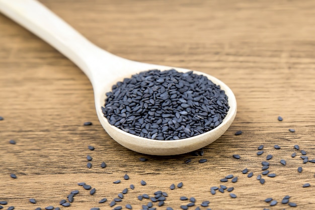 Black sesame seeds in a wooden spoon.