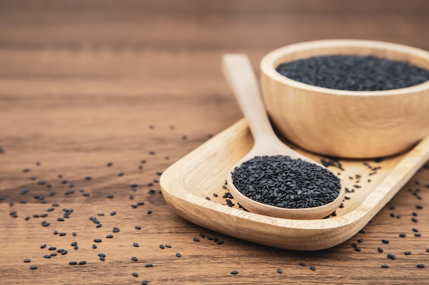 Black sesame seeds in a wooden spoon.