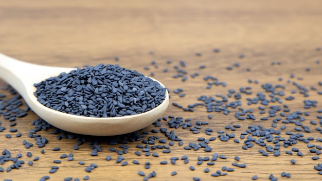 Black sesame seeds in a wooden spoon.