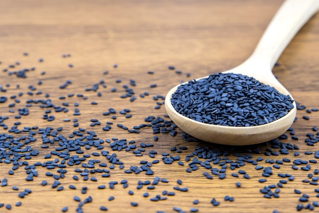 Black sesame seeds in a wooden spoon.