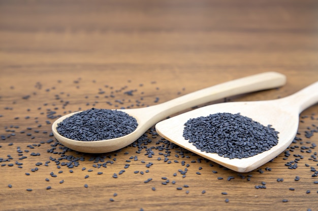 Black sesame seeds in a wooden spoon.