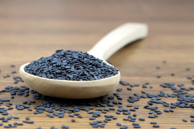 Black sesame seeds in a wooden spoon.