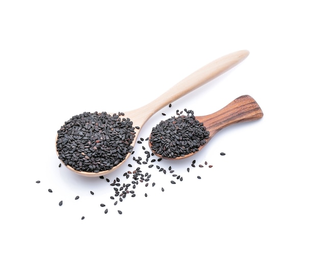 Black sesame in a wooden spoon isolated on white.