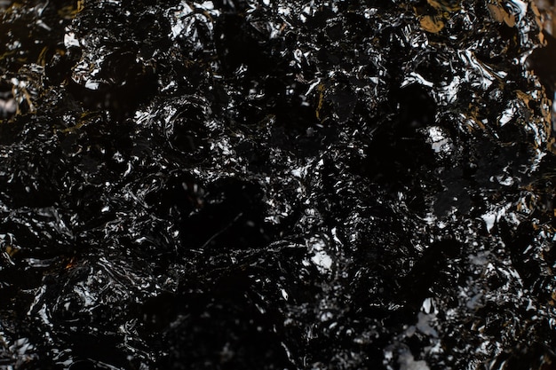 Black shiny charcoal texture, dark background.