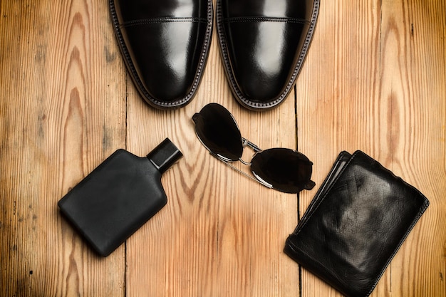 Black shoes sunglasses and a wallet on a wooden table